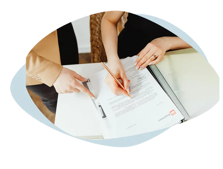 Two people going through a binder of documents, one pointing where to sign