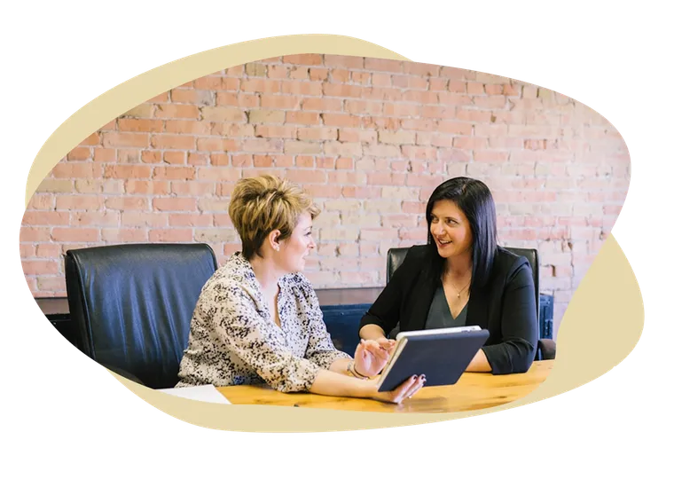 Two people reviewing a plan together on a tablet at a conference table